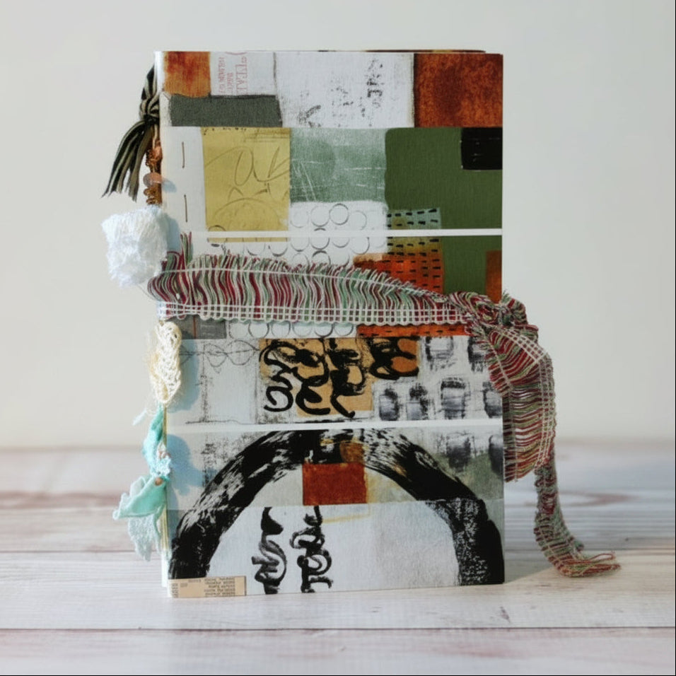 Handmade notebook with colorful collage cover on a wooden surface